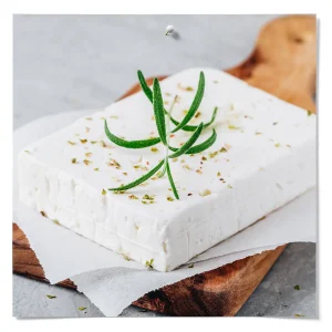 Fresh herb cheese block garnished with rosemary and herbs on parchment paper over a wooden serving board.